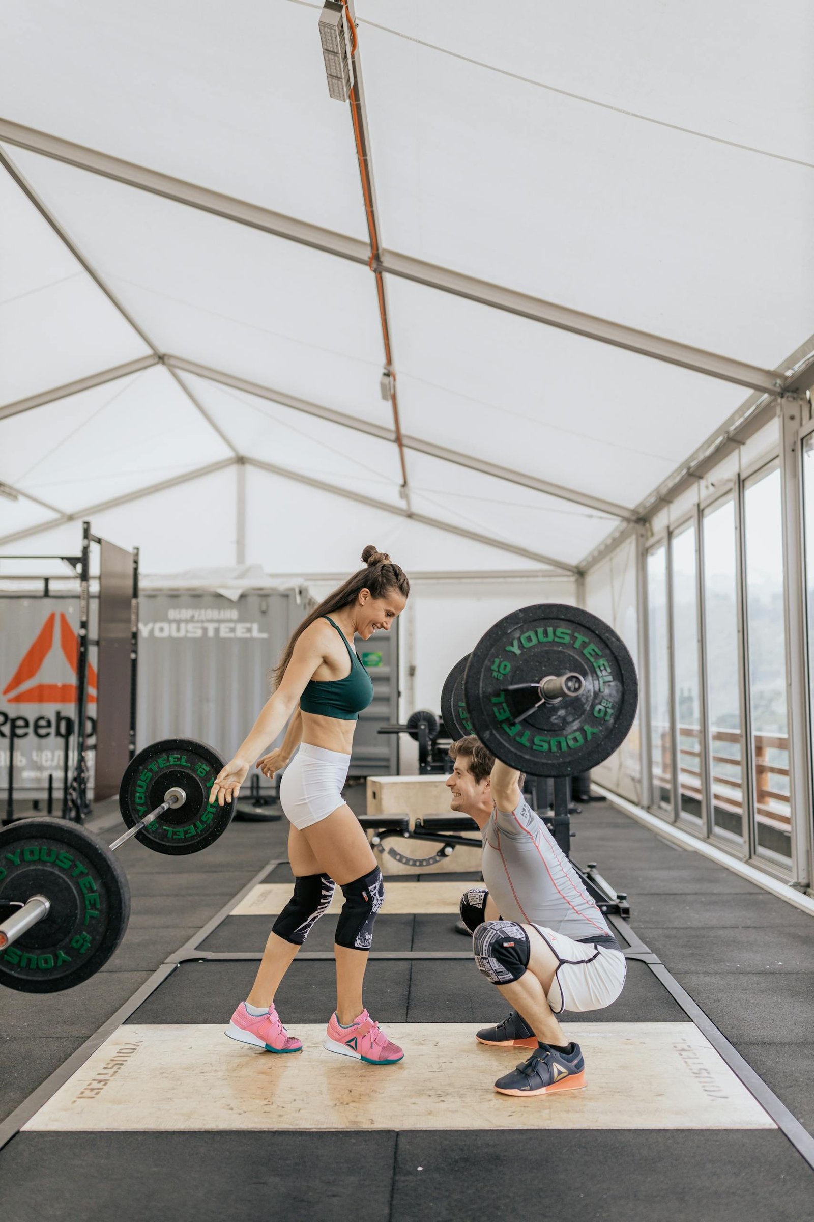 Dynamic weightlifting session with a couple in a modern indoor gym setting.