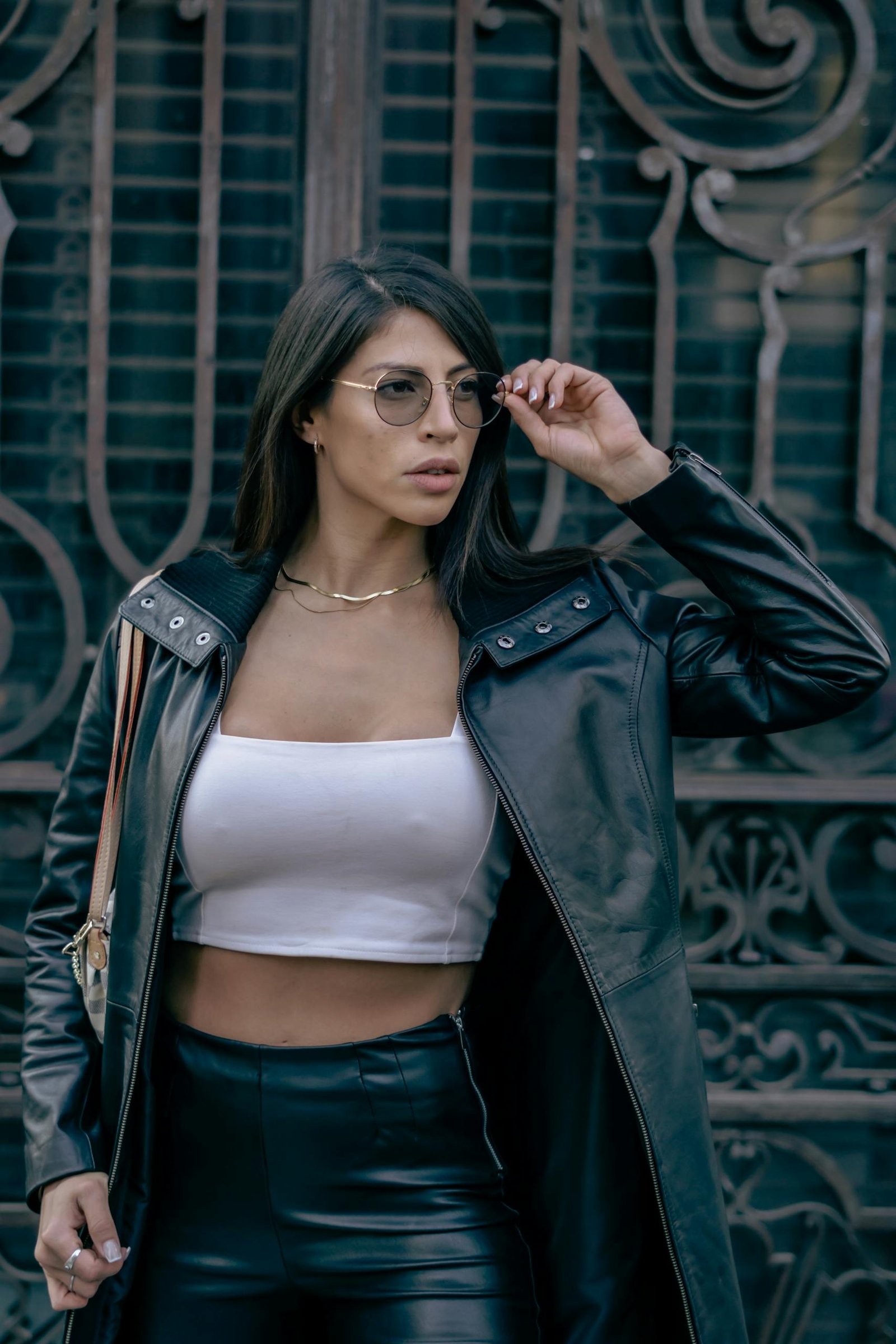 Stylish woman in leather jacket and glasses posing in Mexico City.